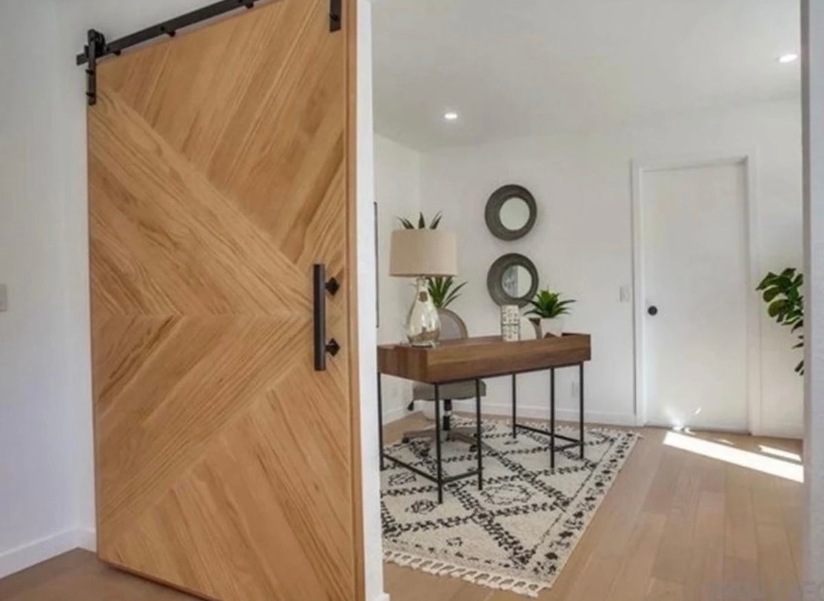 Custom chevron wood sliding door installed in a bright modern entryway.