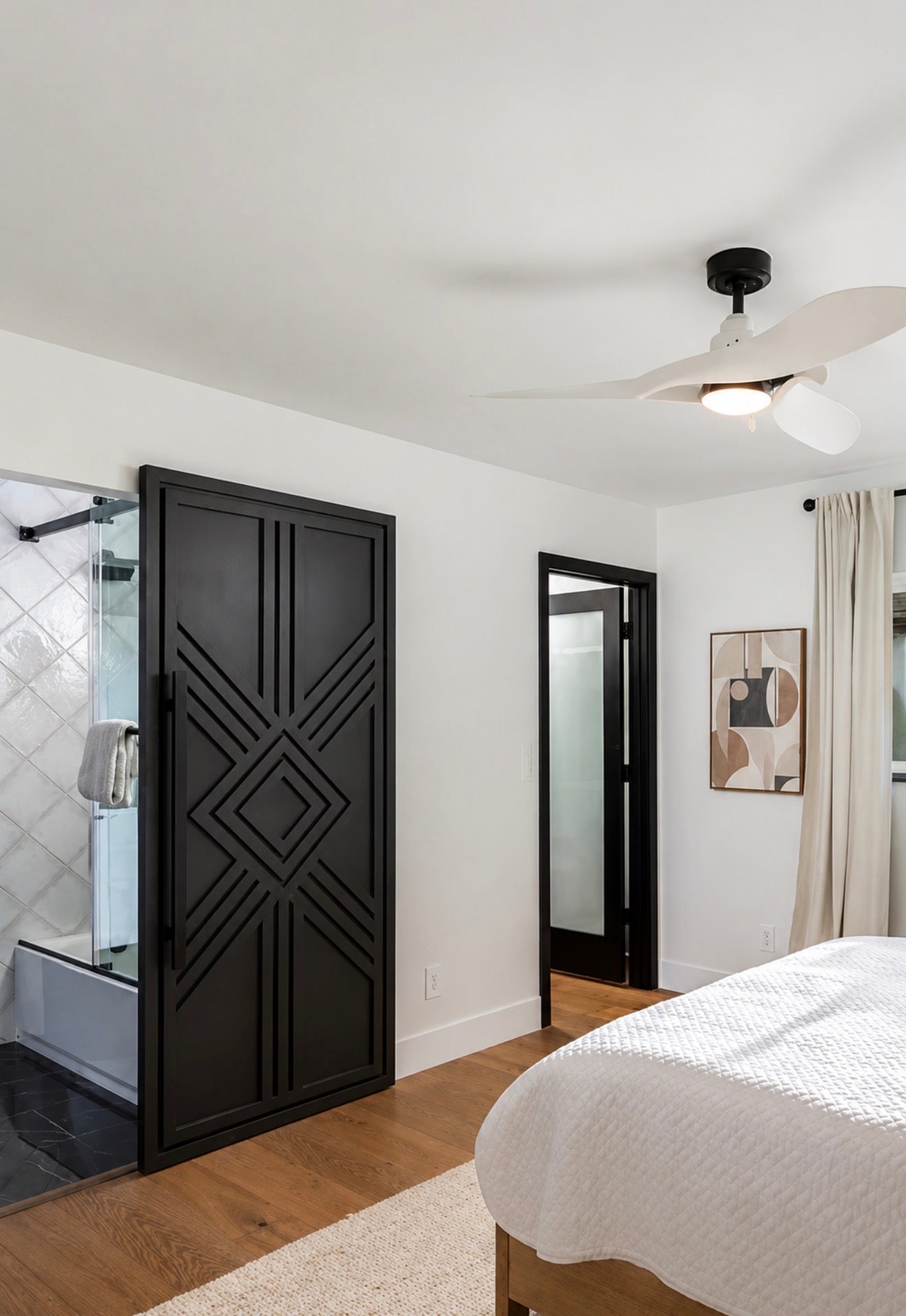 Giza Grand geometric sliding barn door installed between a primary bedroom and bathroom