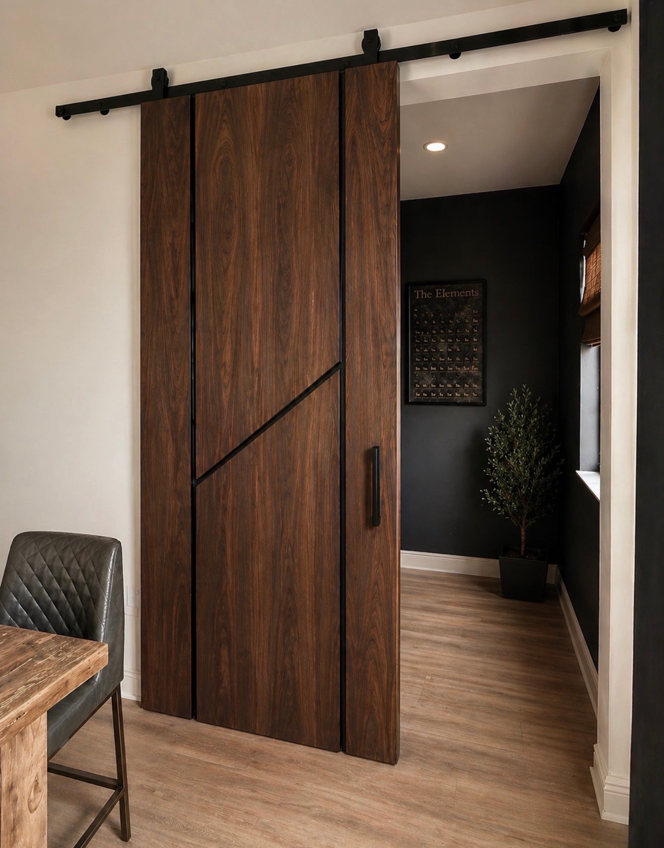 Nerano walnut sliding door with black reveal detail and matte black top mount track installed in modern interior.