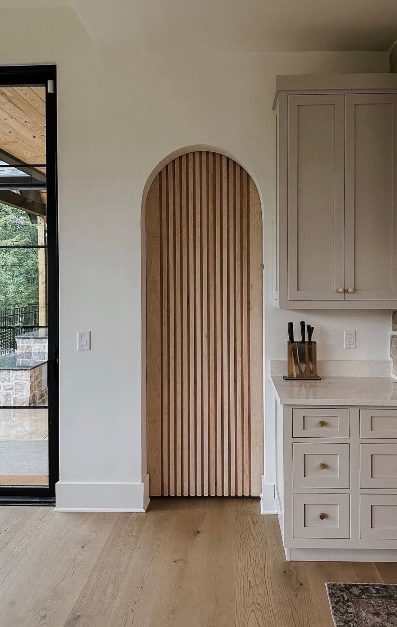 Prestige pocket door frame system installed with modern arched wood slat door.