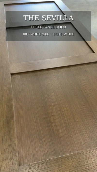 Close-up video of the handcrafted Sevilla three panel interior door in rift white oak with a warm Briarsmoke stain, highlighting the linear wood grain and recessed panel details.